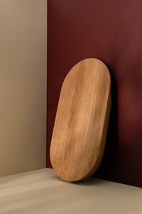 Large wooden cutting board leaning against the burgundy wall on a kitchen counter