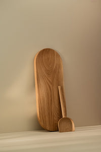 Long wooden cutting board and shovel-like wooden spatula leaning against the wall on the kitchen counter
