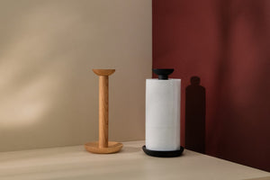 Two wooden paper towel holders, one of which is black and a paper roll on it