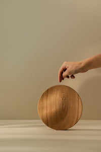 Man spinning round wooden cutting board on a kitchen counter