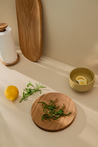 Kitchen counter with lemon and herbs placed on a round wooden cutting board