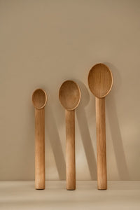 Three wooden spoons of different sizes standing vertically on the kitchen counter